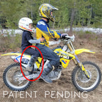 Two people on a yellow dirt bike with a 'Patent Pending' label in a forest setting.